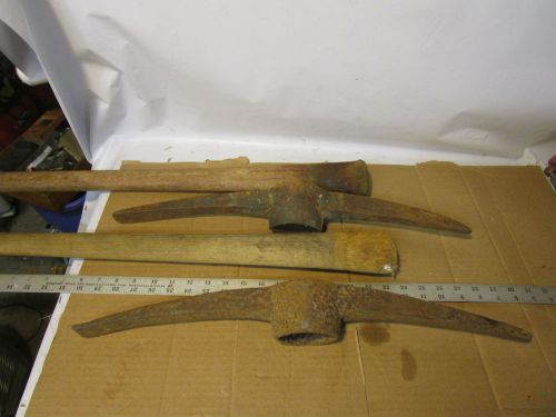 two old heavy pick axe heads with old wood handles vintage tools